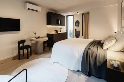a bedroom with a bed and a table and a kitchen at Raibu Antwerp by StayC in Antwerp