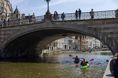 two people kayaking under a bridge on a river at Hostel Uppelink in Ghent
