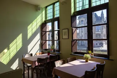 a restaurant with tables and chairs and windows at Hostel Uppelink in Ghent