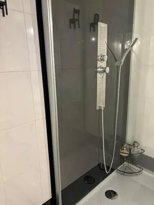 a shower with a glass door in a bathroom at Spacious and Chic 1BR - Separate Kitchen & Washer in Brussels