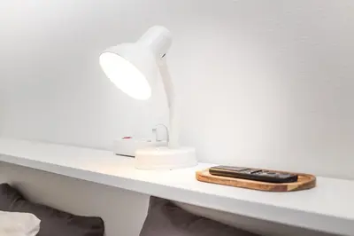 a white table with a lamp and a cell phone on it at Spacious and Chic 1BR - Separate Kitchen & Washer in Brussels