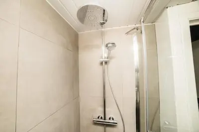 a shower with a glass door in a bathroom at Spacious and Chic 1BR - Separate Kitchen & Washer in Brussels