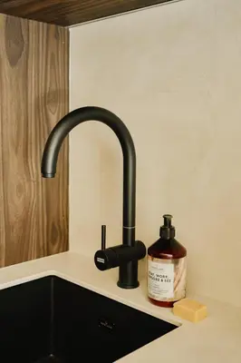 a kitchen sink with a black faucet and a bottle of soap at Raibu Ghent by StayC in Ghent