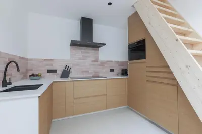 an attic kitchen with wooden cabinets and a staircase at Southside Suites in Antwerp
