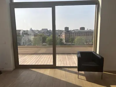 a black chair sitting in front of a large window at Splendid Penthouse in City Center with Water View in Brussels