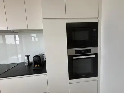 a kitchen with white cabinets and a microwave and a counter at Splendid Penthouse in City Center with Water View in Brussels