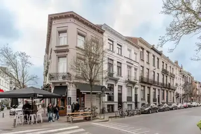 a building on a city street with tables and an umbrella at Elegant Stay in Châtelain Ixelles in Brussels