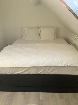 a bed with white sheets and pillows in a room at Only For Tomorrowland in Boom
