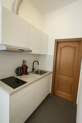 a kitchen with white cabinets and a sink and a door at Cosy studio Midi station in Brussels