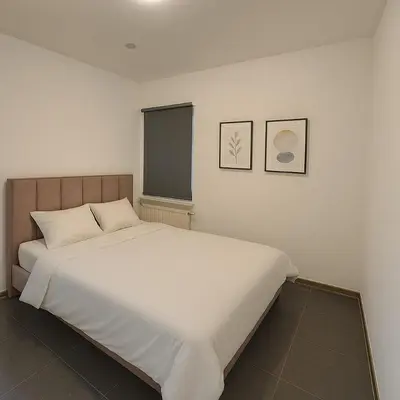 a bedroom with a large white bed with two pictures on the wall at Cosy studio Midi station in Brussels