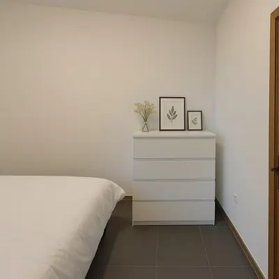 a bedroom with a white bed and a dresser at Cosy studio Midi station in Brussels