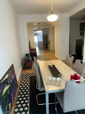 a dining table and chairs in a living room at Le Flagey green place in Brussels