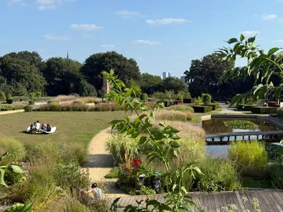 people sitting in a park with a pond and trees at Bruxelles Cozy Atomium Expo in Brussels