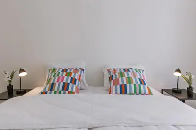 a bedroom with a white bed with two colorful pillows at Bruxelles Cozy Atomium Expo in Brussels