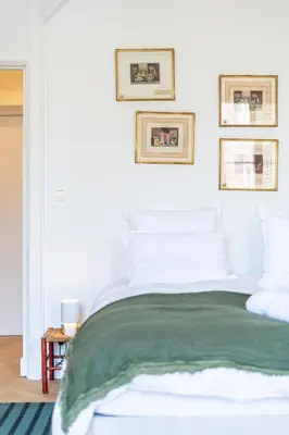 a bedroom with a white bed with a green blanket at Les Appartements du Sablon in Brussels