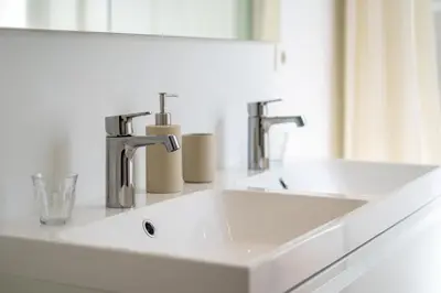 a bathroom sink with two faucets and a mirror at Les Appartements du Sablon in Brussels