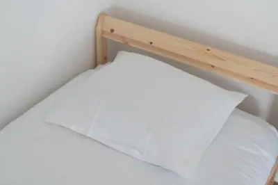 a bed with a wooden frame and a white pillow at Cocon douillet à Bruxelles in Brussels