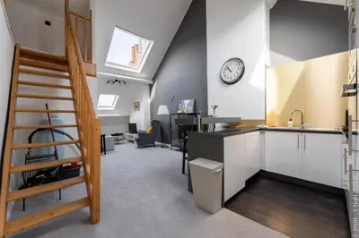 an attic kitchen and living room with a clock on the wall at Cocon douillet à Bruxelles in Brussels