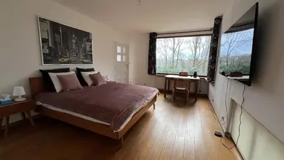 a bedroom with a bed and a large window at PepperLake in Overijse