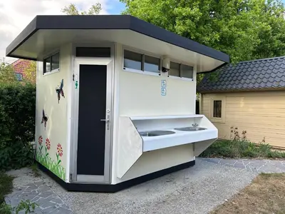 a out house with a sink in a yard at Trekkershutten - Camping Groenpark in Zele