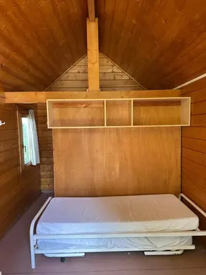 a bed in a wooden room with shelves at Trekkershutten - Camping Groenpark in Zele