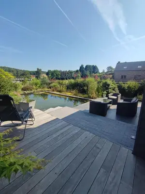 a wooden deck with chairs and a pond at Naturedegrez in Grez-Doiceau