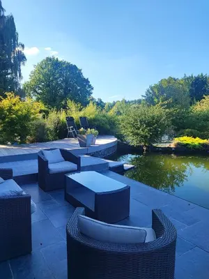 a patio with couches and chairs next to a lake at Naturedegrez in Grez-Doiceau