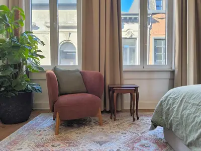 a bedroom with a chair and a table and windows at Charming Family Townhouse in Antwerp in Antwerp