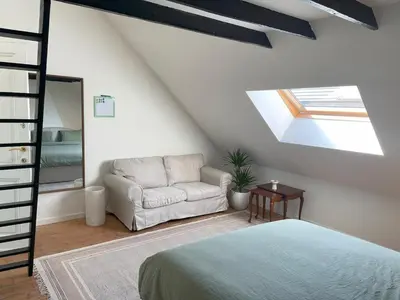 a bedroom with a bed and a chair and a window at Charming Family Townhouse in Antwerp in Antwerp