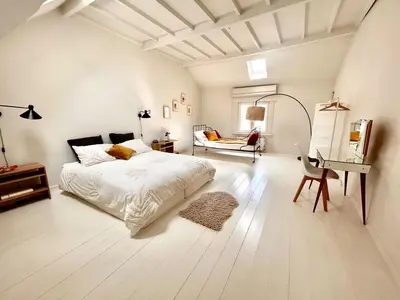 a white bedroom with a bed and a desk at Heart of Antwerp House in Antwerp