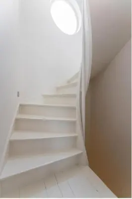 a white staircase with a round window in a room at Heart of Antwerp House in Antwerp