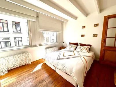 a bedroom with a large bed and two windows at Heart of Antwerp House in Antwerp