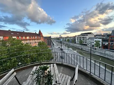 a bridge over a river with a bench and buildings at Sleep & Explore Brussels in Brussels