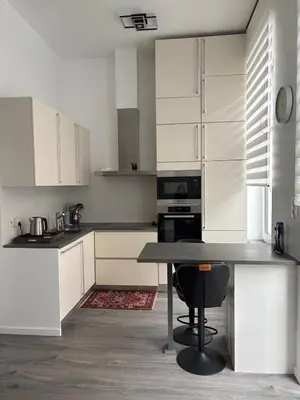 a kitchen with white cabinets and a black table at Modern 1 bedroom and sofa bed stay in Brussels