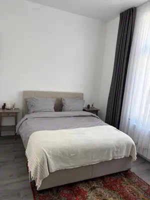 a white bedroom with a large bed and a rug at Modern 1 bedroom and sofa bed stay in Brussels