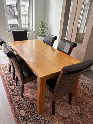 a wooden table with chairs around it on a rug at Modern 1 bedroom and sofa bed stay in Brussels
