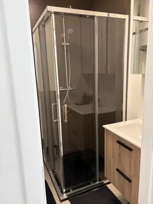 a glass shower in a bathroom with a sink at Modern 1 bedroom and sofa bed stay in Brussels