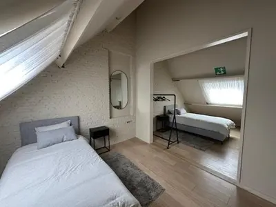 a bedroom with a large bed and a mirror at Luxe Duplex te Koningshooikt in Koningshooikt