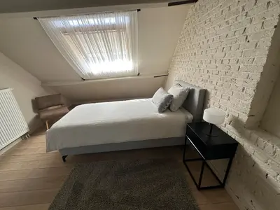 a bedroom with a bed and a brick wall at Luxe Duplex te Koningshooikt in Koningshooikt