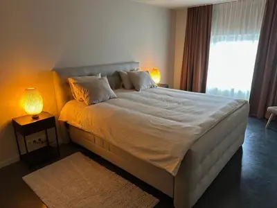 a bedroom with a large white bed with a window at Luxe Duplex te Koningshooikt in Koningshooikt