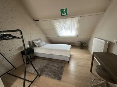 a small bedroom with a bed and a window at Luxe Duplex te Koningshooikt in Koningshooikt