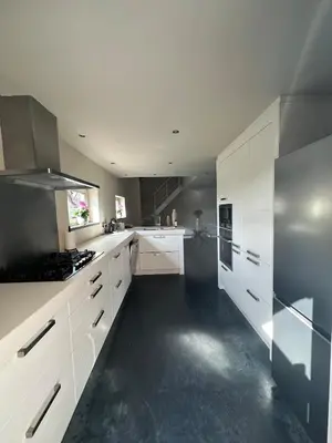 a large white kitchen with white cabinets and appliances at Luxe Duplex te Koningshooikt in Koningshooikt