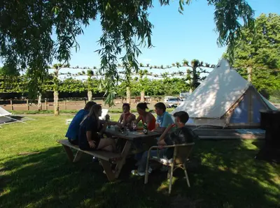 a group of people sitting at a table in front of a tent at Glamping Josephine in Geel