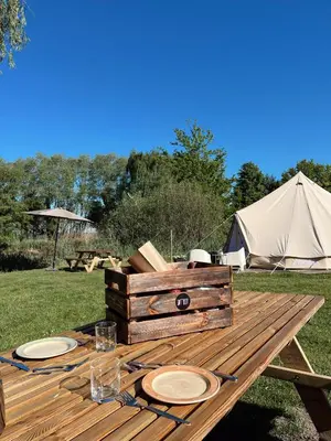 a wooden picnic table with plates and a tent at Glamping Josephine in Geel