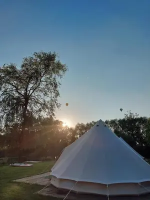 a white tent in a field with the sun in the background at Glamping Josephine in Geel