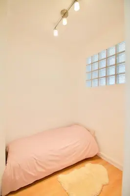 a bed in a white room with a rug and a window at Very nice & large studio-Plasky in Brussels