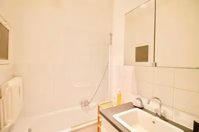 a white bathroom with a sink and a tub at Very nice & large studio-Plasky in Brussels