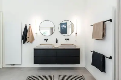 a bathroom with a black vanity and two mirrors at Paviljoen De Notelaer in Bornem