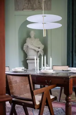 a dining room with a table and a chandelier at Paviljoen De Notelaer in Bornem