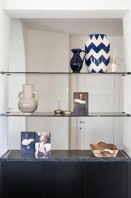 a glass shelf with pictures and vases on it at Paviljoen De Notelaer in Bornem
